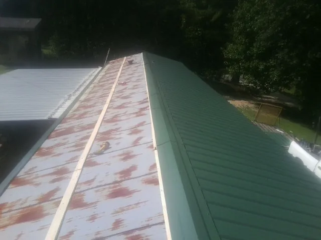 Old rusted panels beside newly installed green metal roofing — Wind Damage Roof Repair by Roofing Brothers in Divide